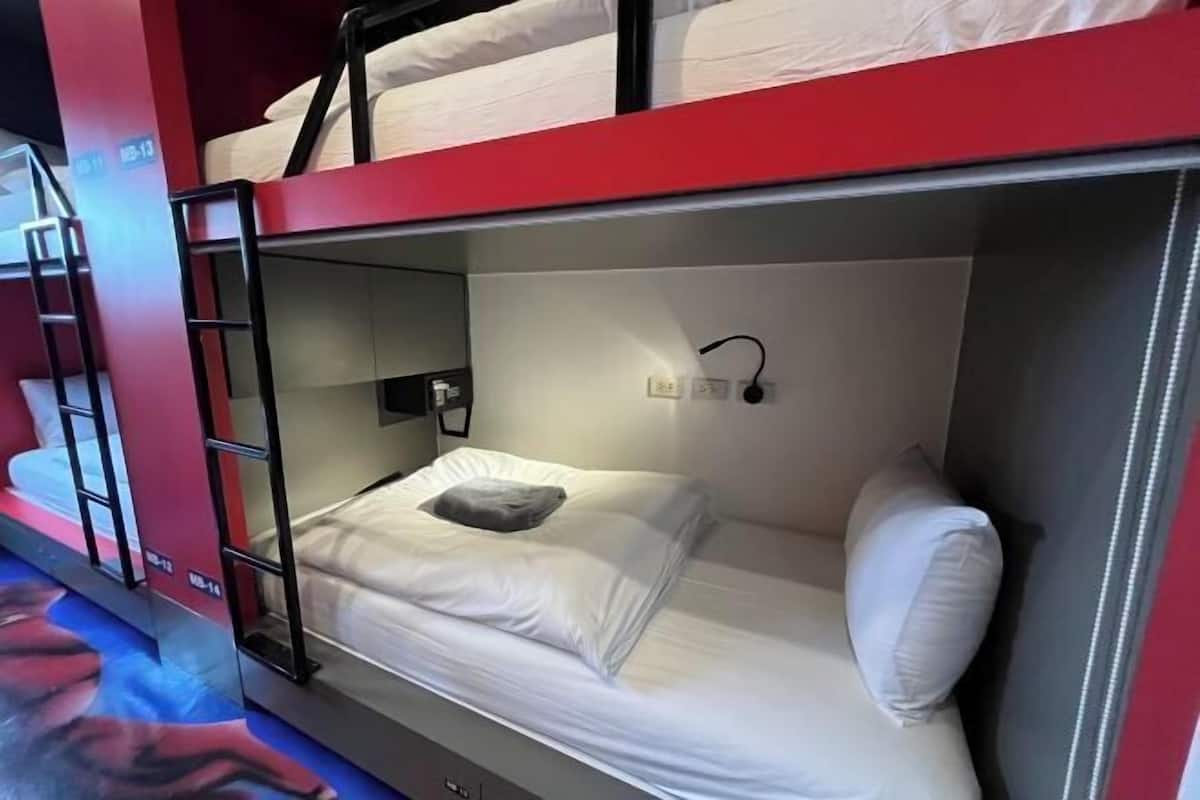 Ein Stockbett mit einer Leiter, einer Wandleuchte und einem kleinen Regal.