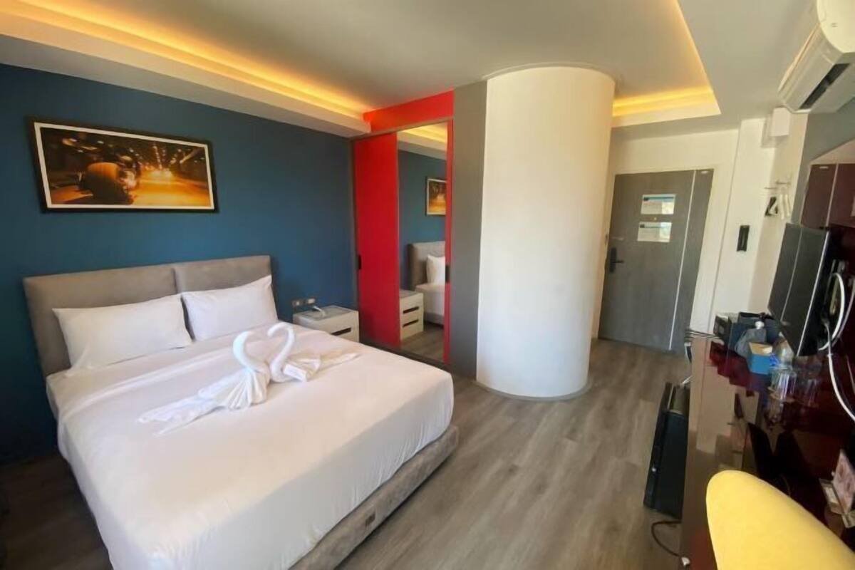 Ein Hotelzimmer mit Bett, Schreibtisch, Stuhl, Fernseher und einer Tür.