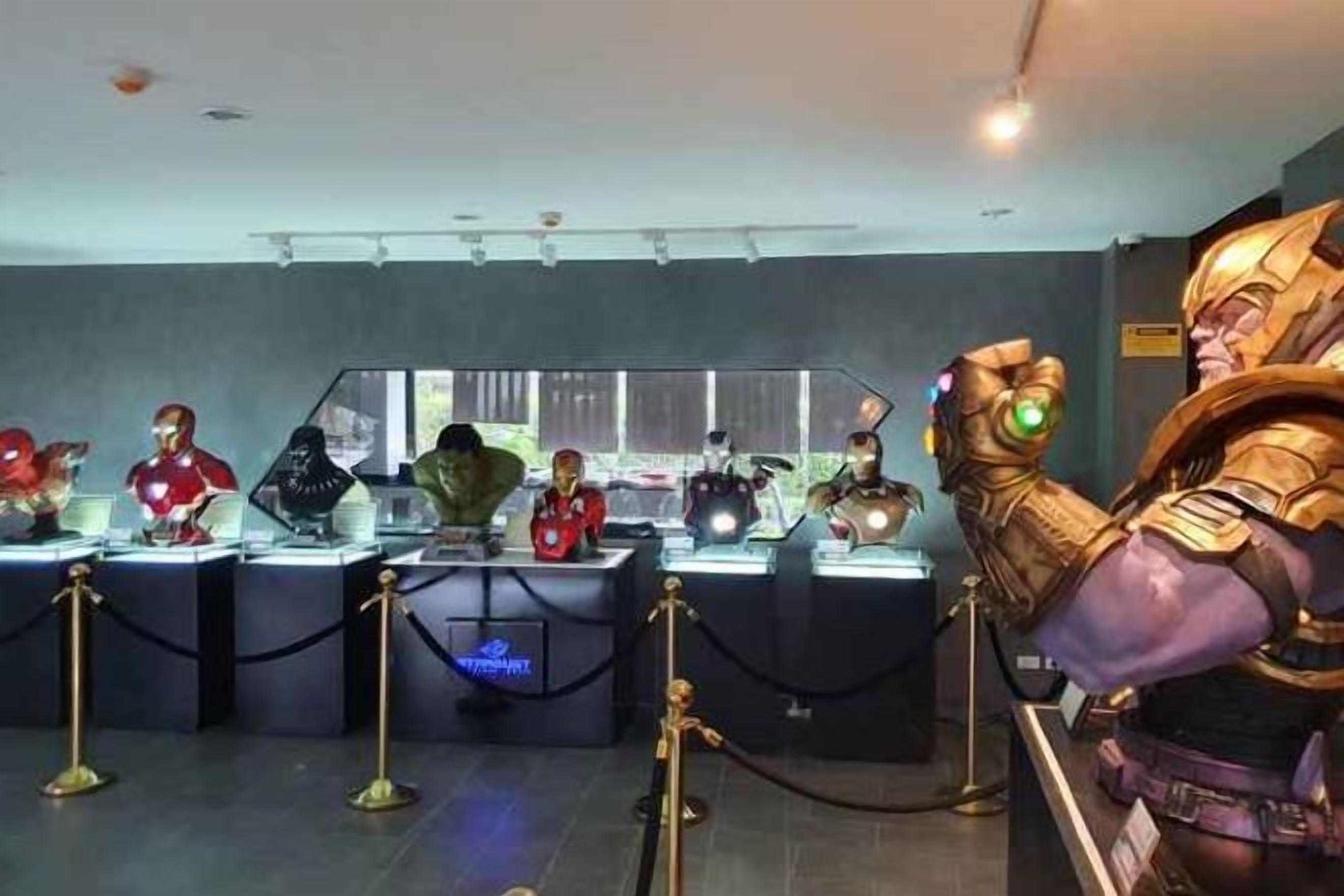 Esposizione di varie action figure e oggetti da collezione su piedistalli in vetro, ognuno separato da una cordonata nera.