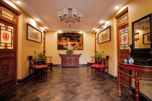 Un hall tradicional al estilo chino con un mostrador de recepción, sillas y un piano.