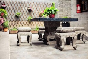 Una mesa de piedra con taburetes a juego en un patio.