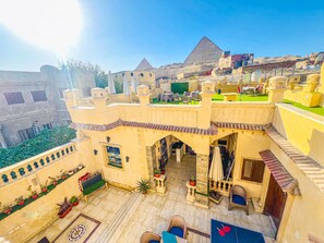 A rooftop terrace with a view of a pyramid, furnished with outdoor seating and potted plants. - Sidi Hamad Pyramids View (Giza)