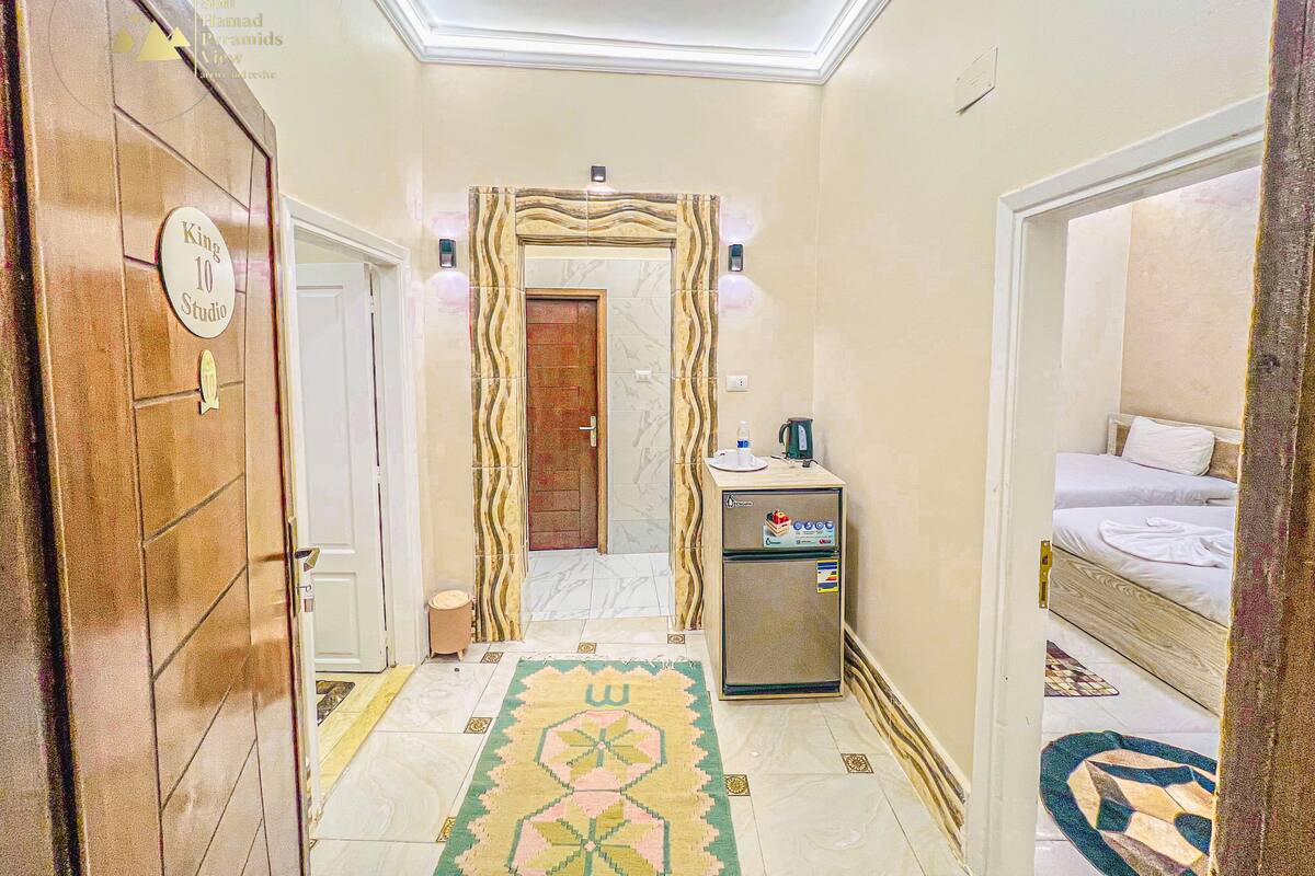 Pasillo de hotel con una habitación Estudio King 10, un minibar y una cama con alfombra estampada.