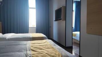A hotel room with two beds, a TV, and a mirror.