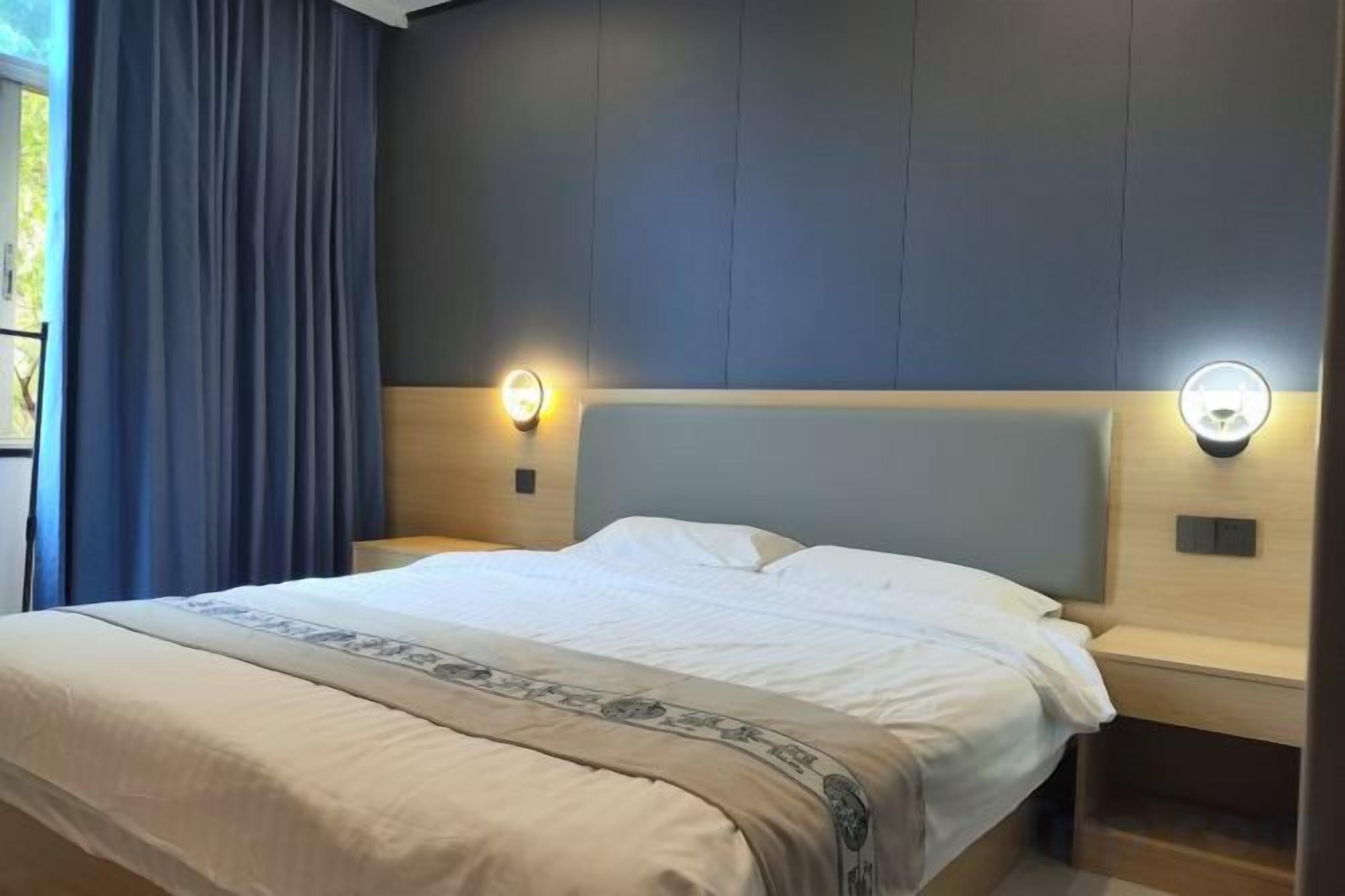 A hotel room with a bed, bedside lamps, and a headboard.