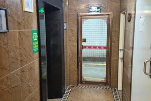 Un ascensor con una pared de azulejos, un letrero verde y una puerta con un letrero rojo.