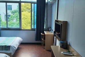 A hotel room with a bed, a desk with a chair, a television, and a window with curtains. - Jiuyuejiu Business Hotel (Tongxiang)