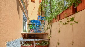 A narrow outdoor space with a blue metal chair and table, surrounded by plants and a wooden fence. - 1 bedroom lovely home in Pieve Ligure (Pieve Ligure)