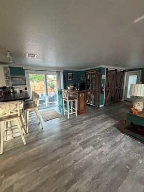 A spacious kitchen with a dining area, wooden flooring, and a view of the outdoors.