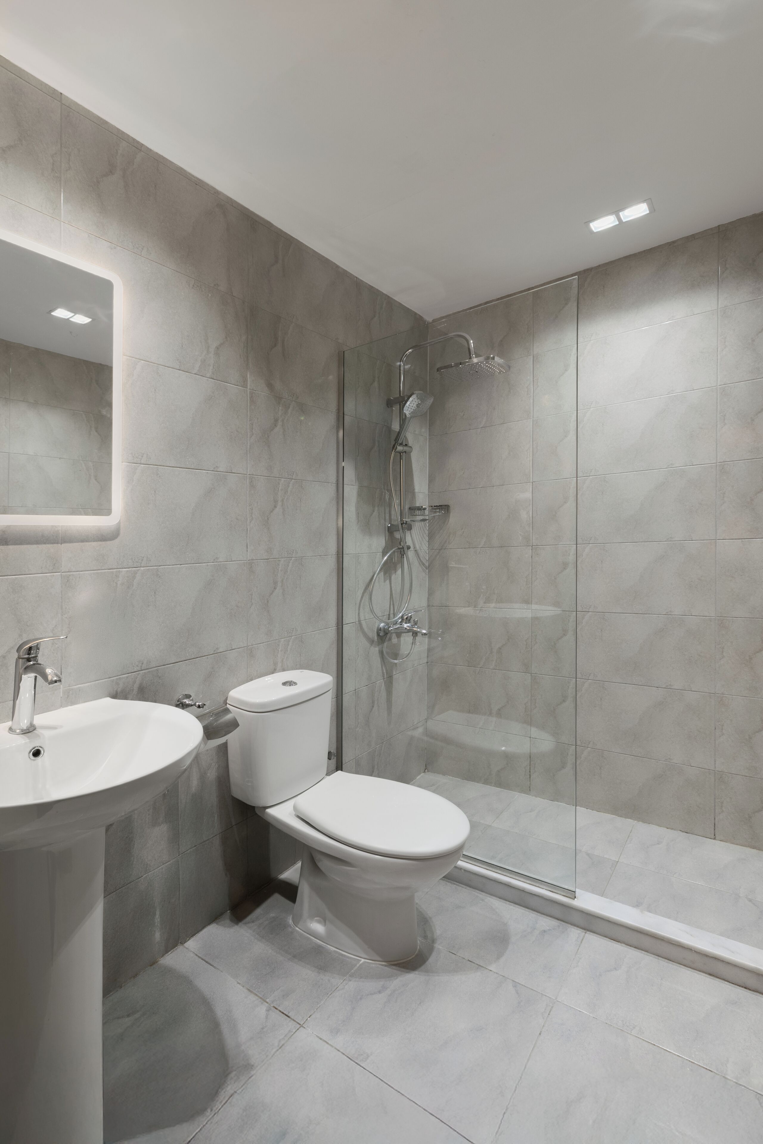 Une salle de bain moderne avec une douche à parois de verre, un lavabo blanc et des toilettes.