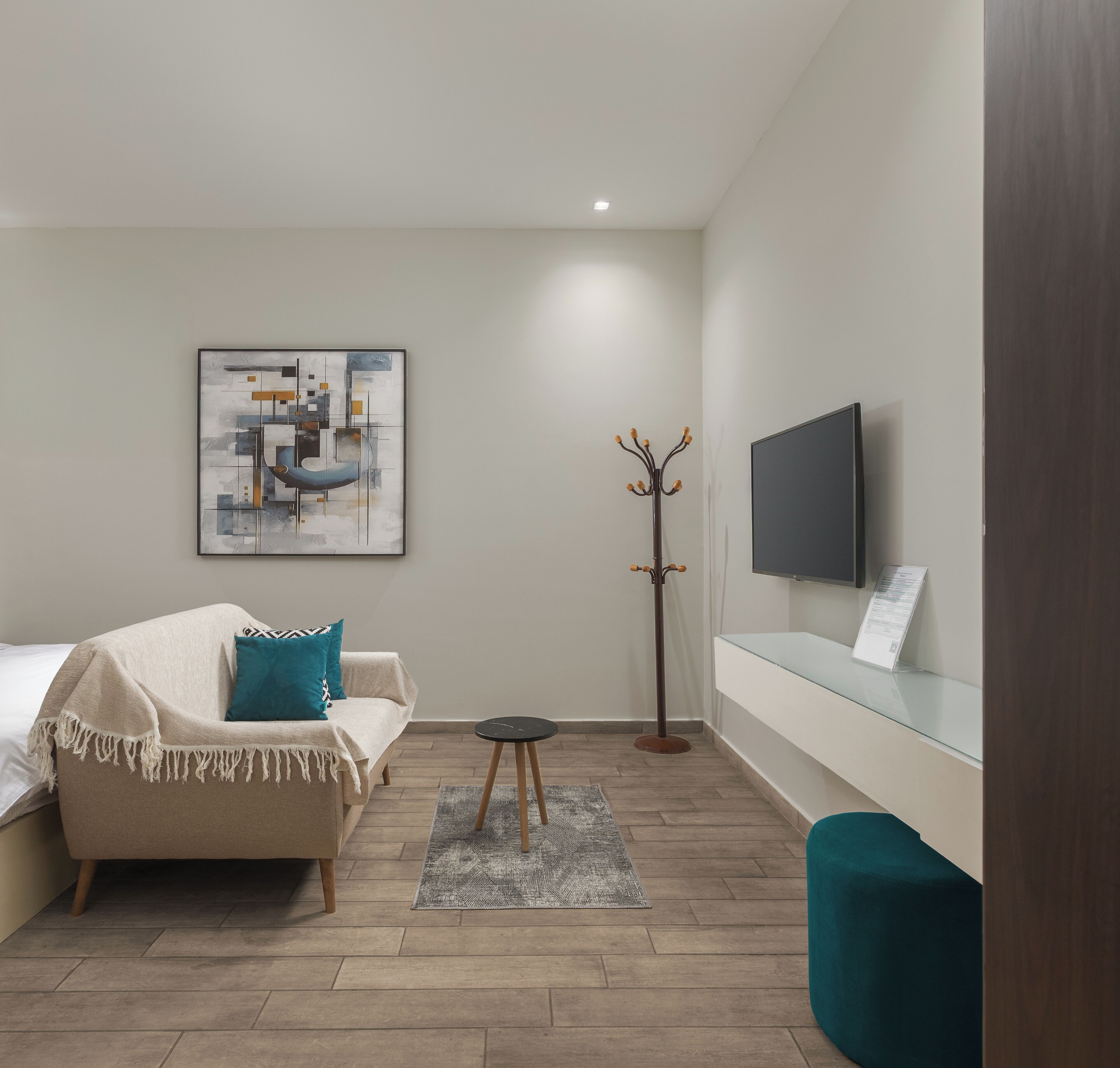 Una habitación moderna con sofá, perchero, mesita y televisor montado en la pared.