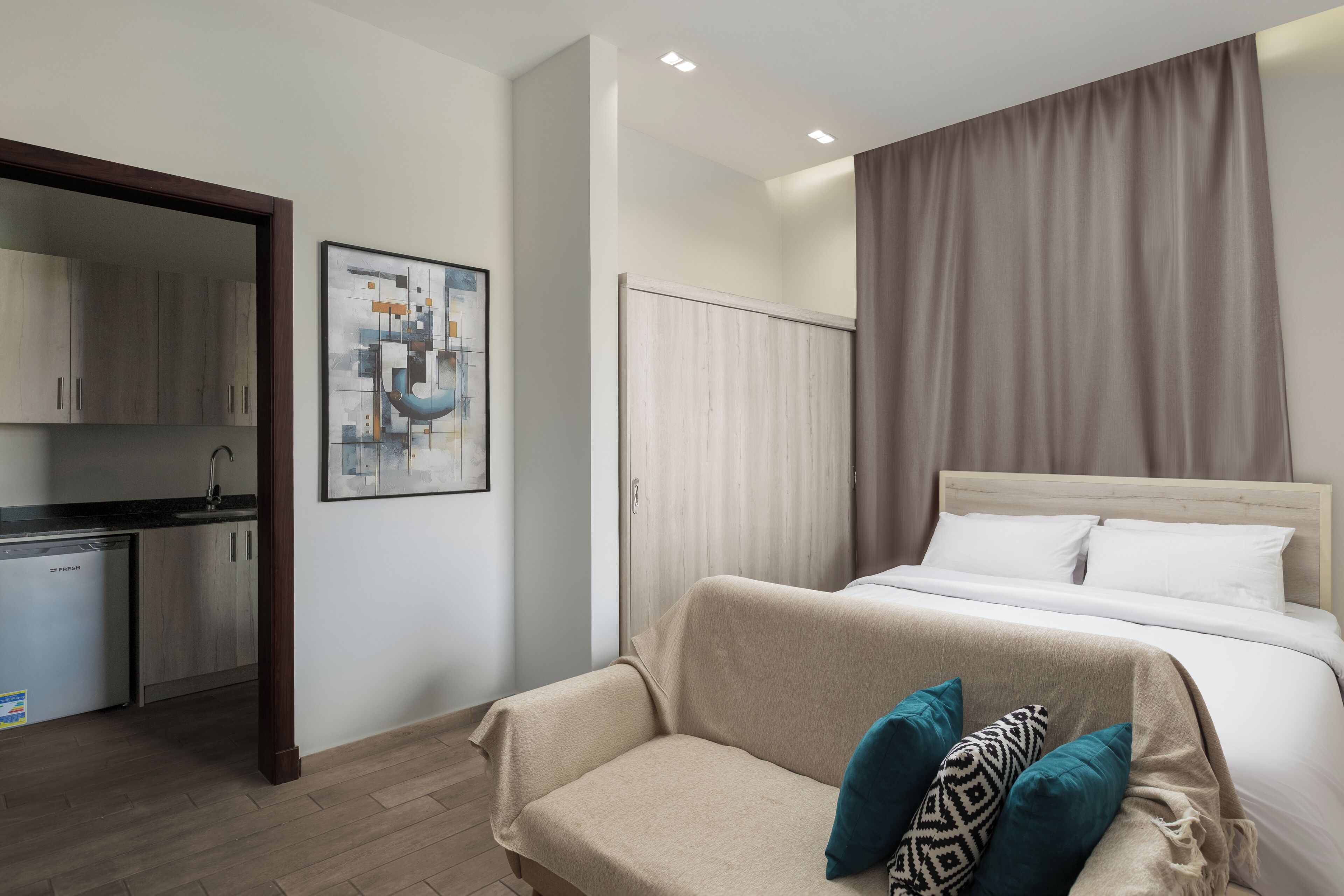 Une chambre avec un lit, un canapé, un tableau et un coin cuisine.