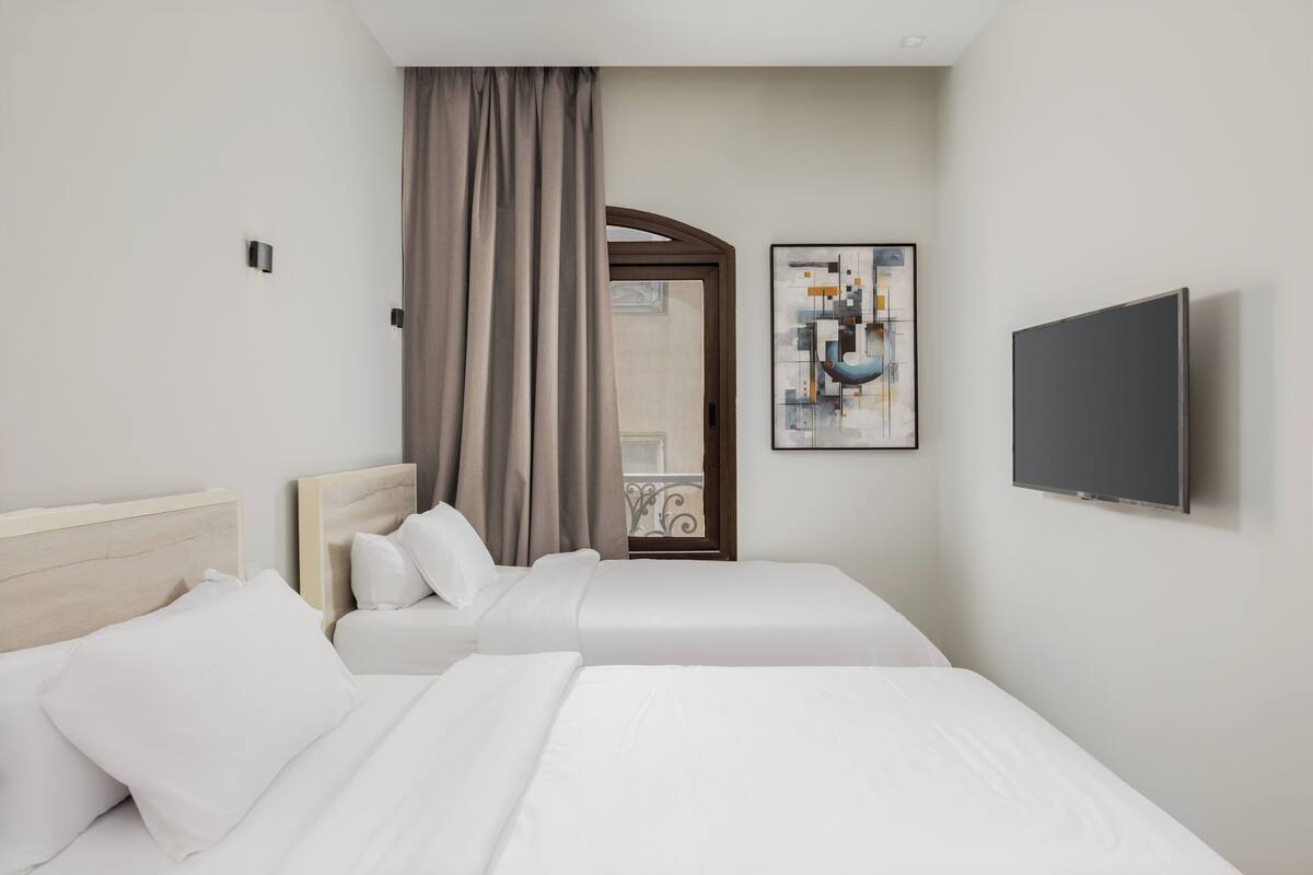 Una habitación de hotel con dos camas, un televisor y un cuadro en la pared.
