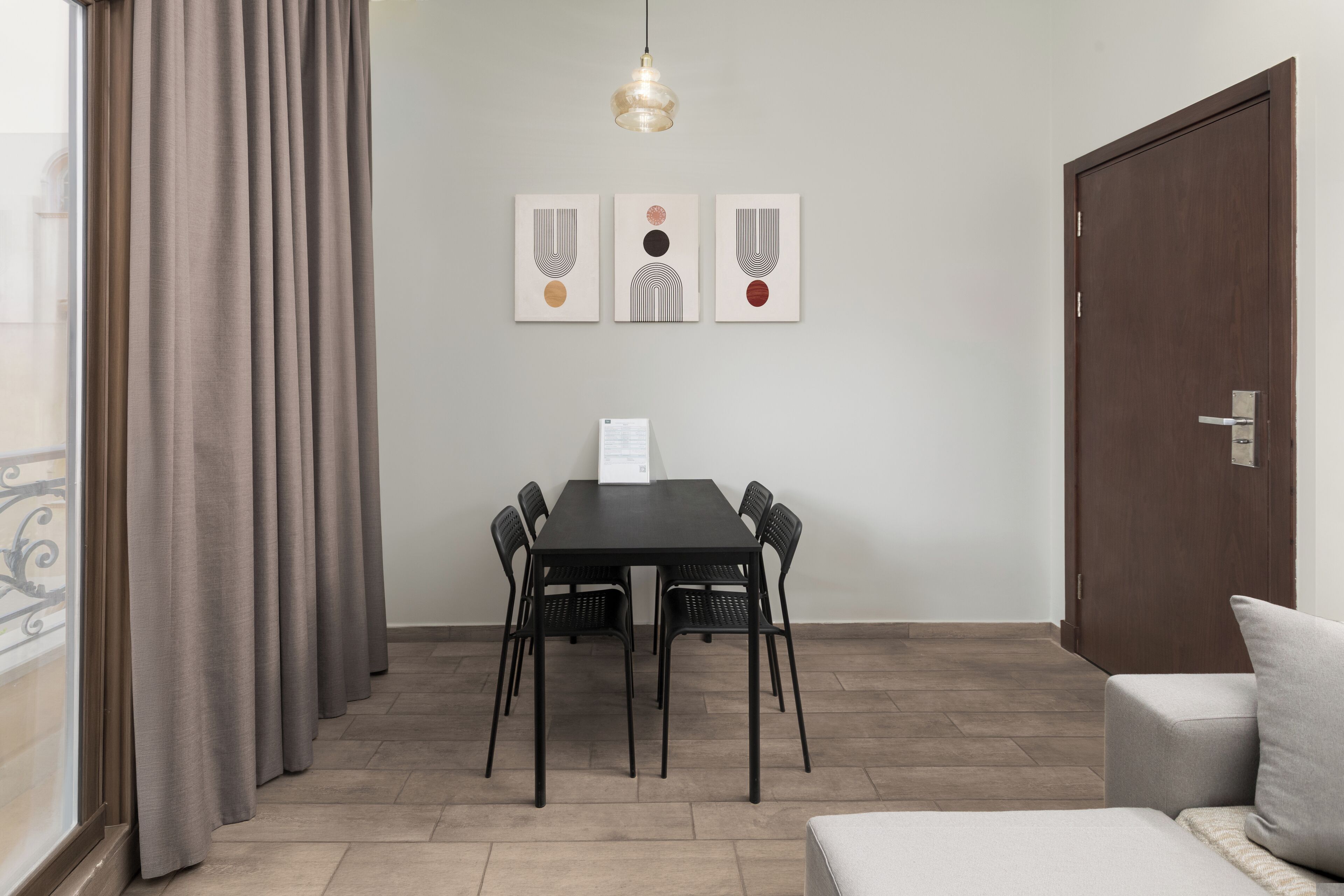 Une pièce comprenant une table à manger, des chaises, un canapé, une porte et des œuvres d’art accrochées au mur.