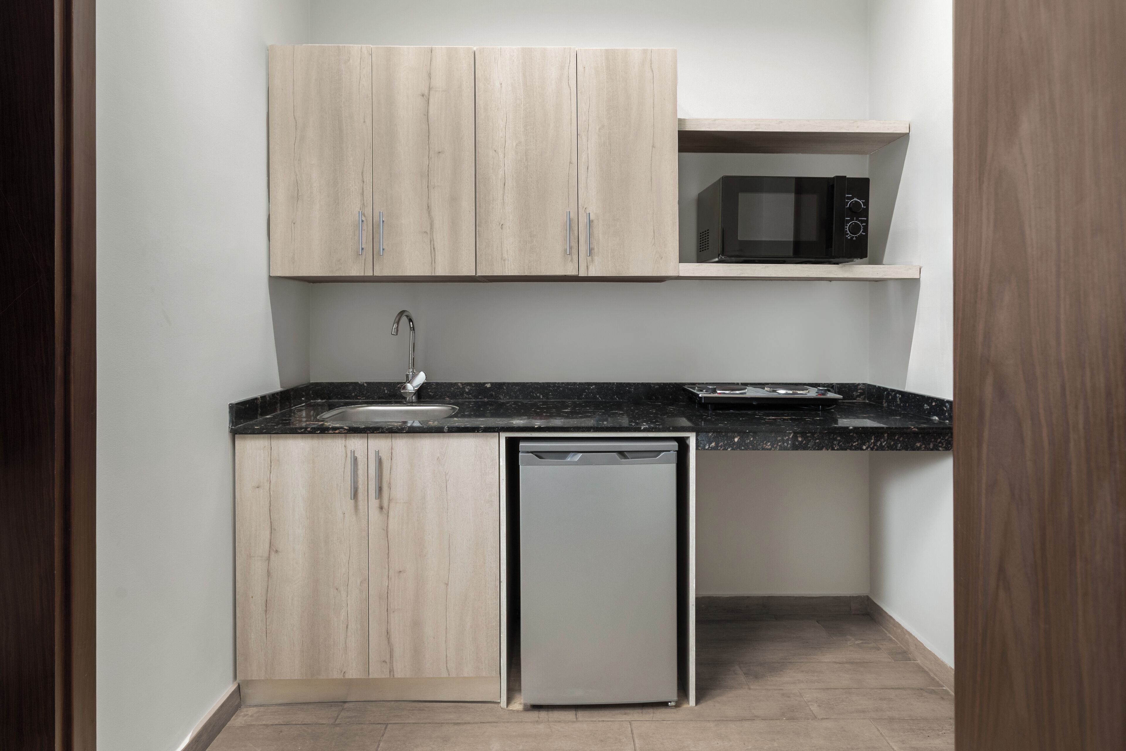 A compact kitchen with wooden cabinets, a built-in microwave, and a dishwasher.