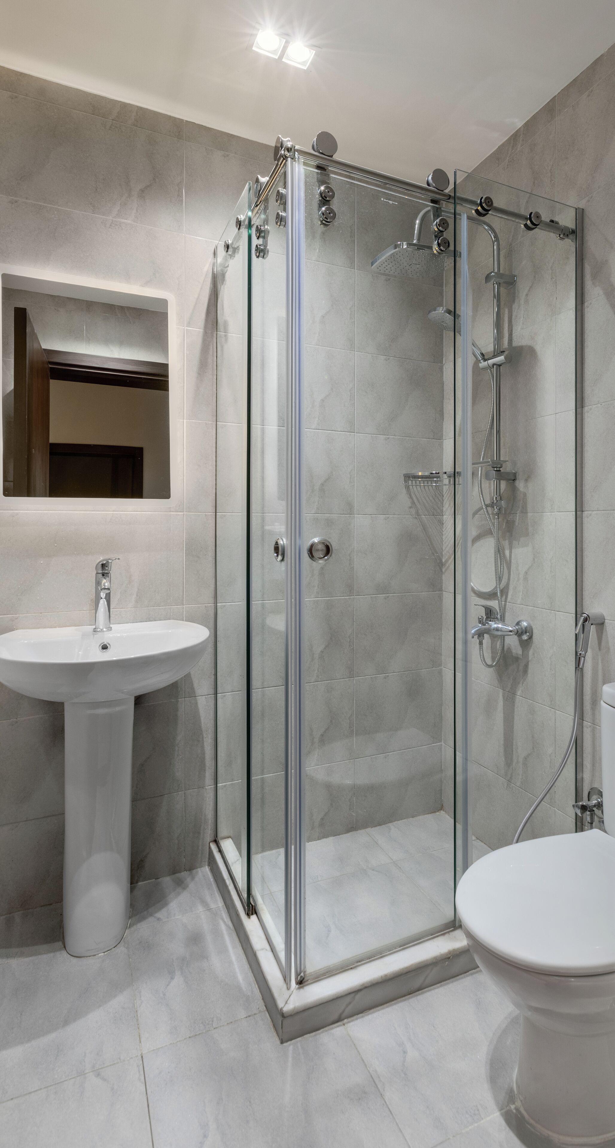 Ein modernes Badezimmer mit einer Duschkabine, einem Standwaschbecken und einer Toilette.