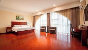 A hotel room with a wooden floor, a bed, two chairs, a desk, and a large window with curtains. - GreenTree Inn (Ganyu Ancient City Yinxing Avenue) (Ju County)