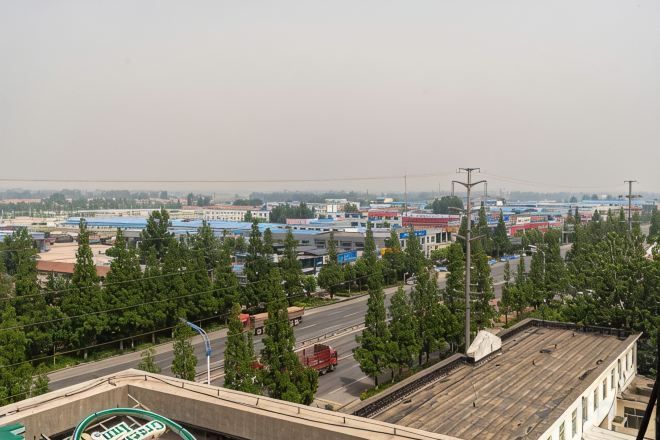 A view of a cityscape with buildings, trees, and a road.