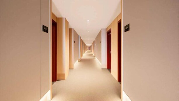 A long, narrow hotel corridor with doors on both sides, leading to individual rooms. - GreenTree Inn (Ganyu Ancient City Yinxing Avenue) (Ju County)