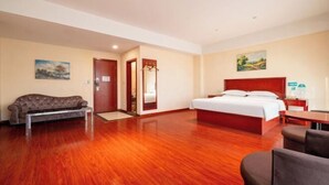 A hotel room with a wooden floor, a bed, a sofa, and a desk. - GreenTree Inn (Ganyu Ancient City Yinxing Avenue) (Ju County)