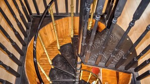 En spiralformet trappe med detaljerede, sorte gelændere og gyldne detaljer.