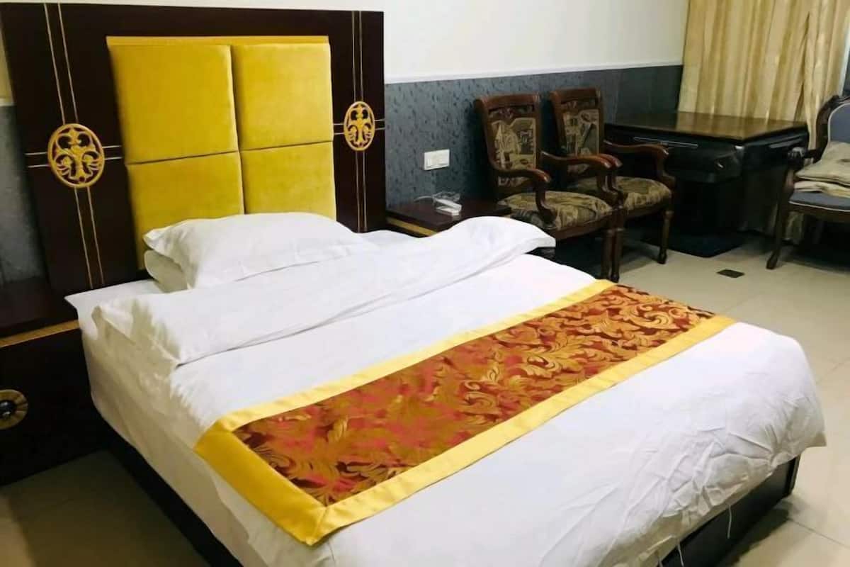 Une chambre d’hôtel comprenant un lit, un bureau, deux chaises et une armoire.