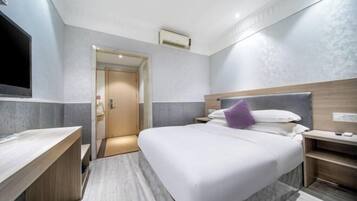 Una habitación de hotel con cama, mesitas de noche, televisor y aire acondicionado.
