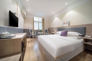 Une chambre d’hôtel comprenant un lit, une table de chevet, un bureau, une chaise et un téléviseur.