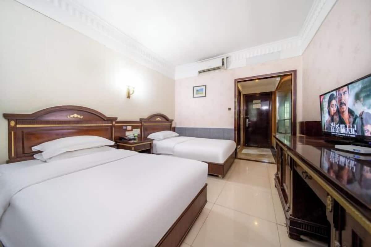 Une chambre d’hôtel avec deux lits, une télévision et un bureau.
