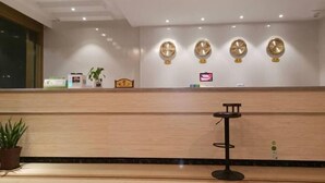 A reception area with a wooden reception desk, a small seating area, and a wall-mounted TV.