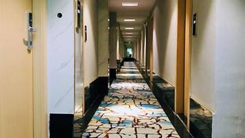 Un pasillo de hotel con alfombra estampada, puertas a ambos lados y un largo recorrido hasta el final.
