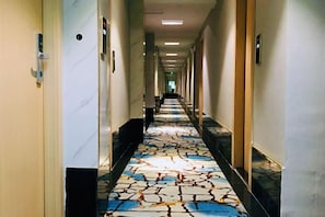 A hotel corridor with a patterned carpet, doors on either side, and a long hallway leading to a distant end. - Zijinghua Hotel (Cixi)