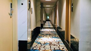 A hotel hallway with a patterned floor, doors on both sides, and a long corridor.