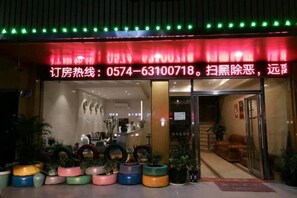 A hotel entrance with a red awning, potted plants, and a visible reception area. - Zijinghua Hotel (Cixi)