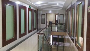 A hotel corridor with glass railings, doors with frosted glass panels, and a ceiling with recessed lighting.