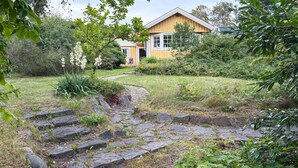 A house with a stone pathway leading to a wooden door, surrounded by lush greenery and a garden. - 3 bedroom gorgeous home in Halmstad (Halmstad)