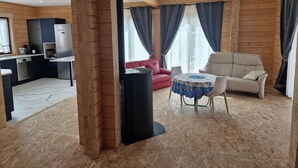 A modern log cabin interior with a kitchen, dining area, and living room. - Eldeweiss Normand (Saint-Marcel)