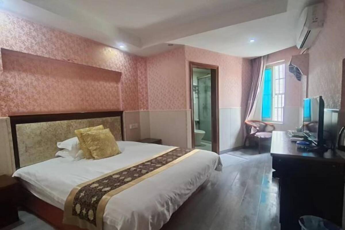 A hotel room with a bed, a desk, a chair, and a bathroom.