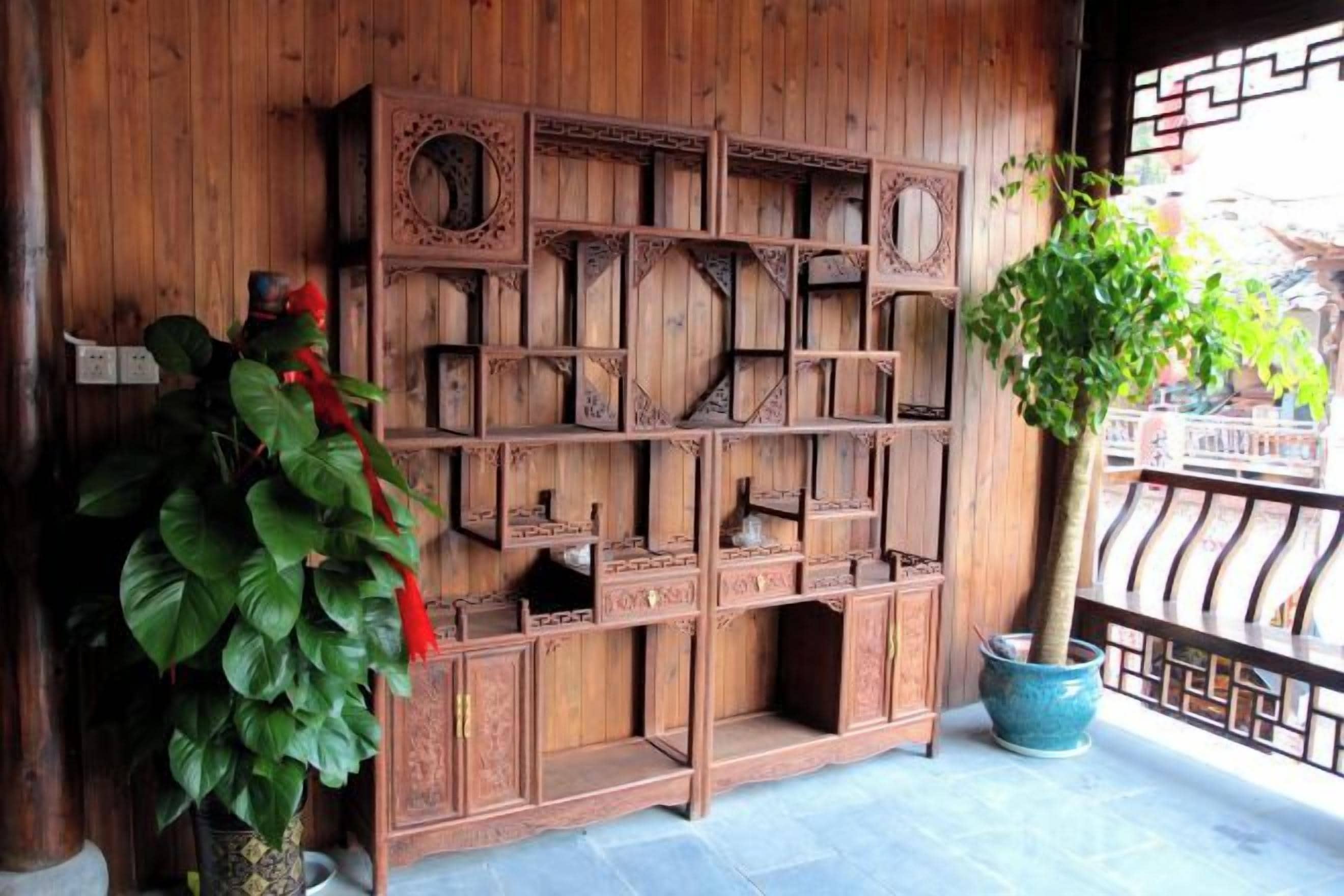 Een houten wand met ingewikkelde houtsnijwerken en een bloempot.