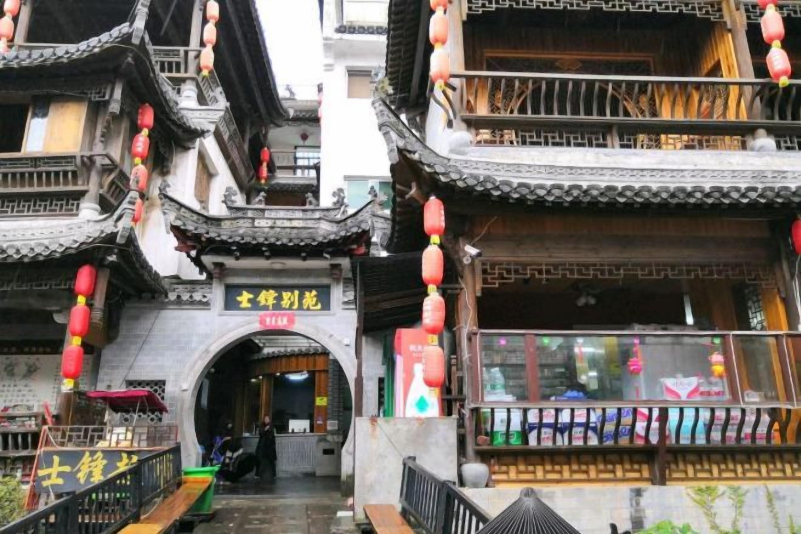 A traditional Chinese building with a tiled roof, an archway entrance, and red lanterns.