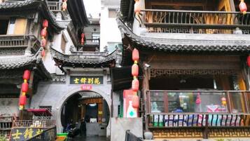 A traditional Chinese building with a tiled roof, an archway entrance, and red lanterns.