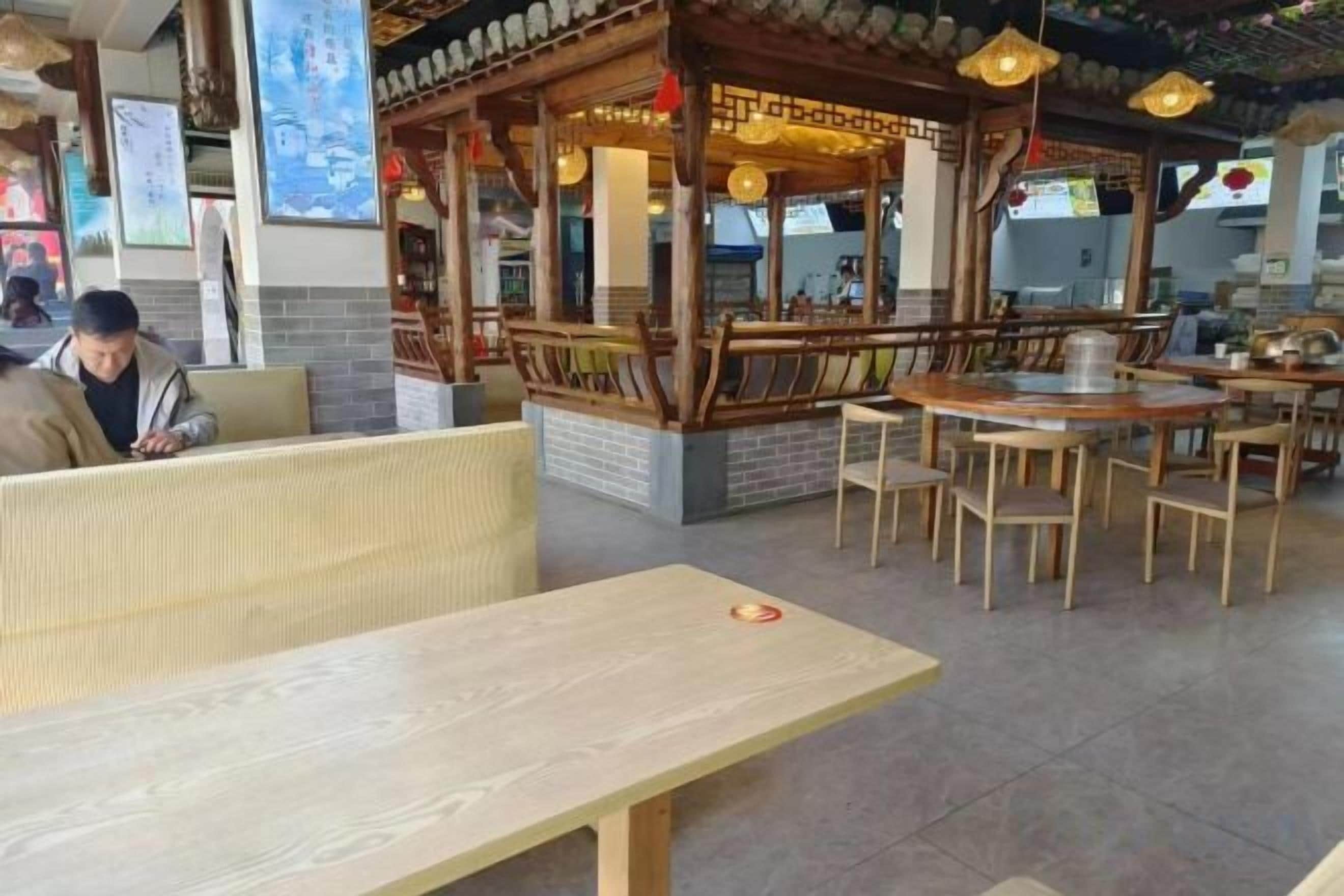 Een restaurantinterieur met houten meubels, een traditionele zithoek in Aziatische stijl en een balie.
