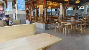 Een restaurantinterieur met houten meubels, een traditionele zithoek in Aziatische stijl en een balie.