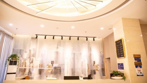 A reception area with a modern chandelier, a reception desk, and a glass partition.