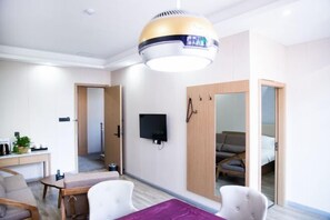 Una habitación de hotel moderna con comedor, televisor montado en la pared y un espejo grande.
