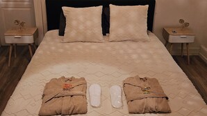 Una cama bien hecha con una colcha estampada, dos toallas dobladas sobre la cama y una pared decorada con un diseño de luna.