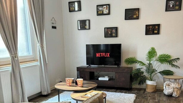 Una sala de estar moderna con un sofá capitonado, un televisor de pantalla plana, una mesa de centro y una planta en maceta.