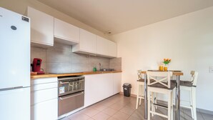 A modern kitchen with white cabinets, stainless steel appliances, and a wooden countertop.