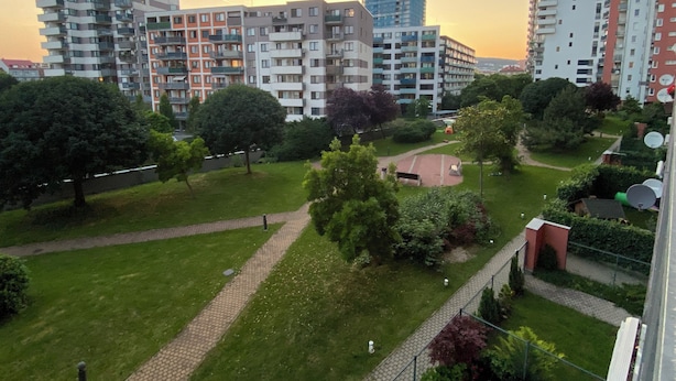 Ein Wohngebiet mit mehrstöckigen Wohngebäuden, einem Park mit gepflastertem Weg und Grünflächen.