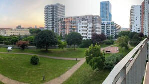 Ein Wohngebiet mit modernen Mehrfamilienhäusern, einem gepflegten Park mit Rasenflächen und einem befestigten Gehweg.